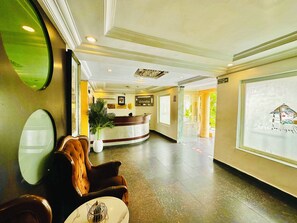 A hotel lobby with a reception desk, seating area, and a large window. - Presken Bank Anthony (Lagos)