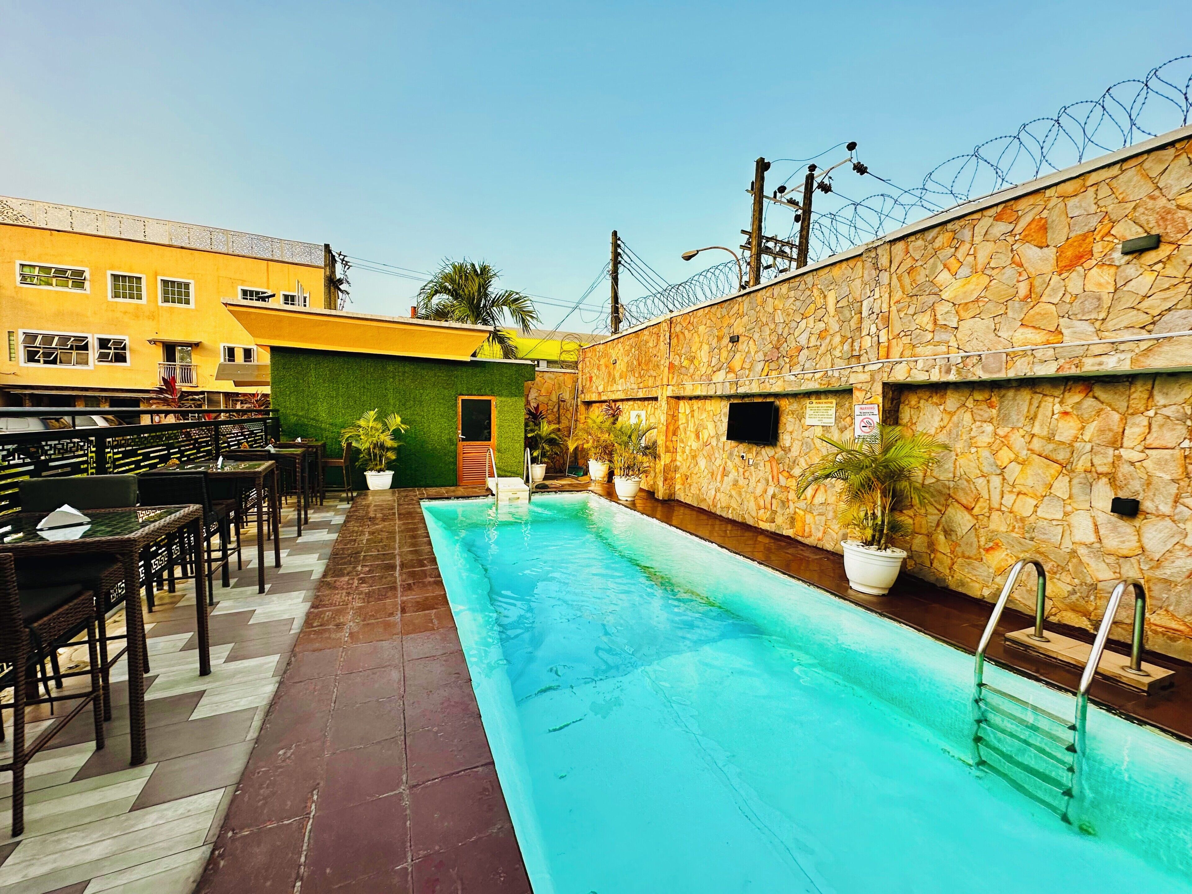 A swimming pool with a stone wall and a barbed wire fence.