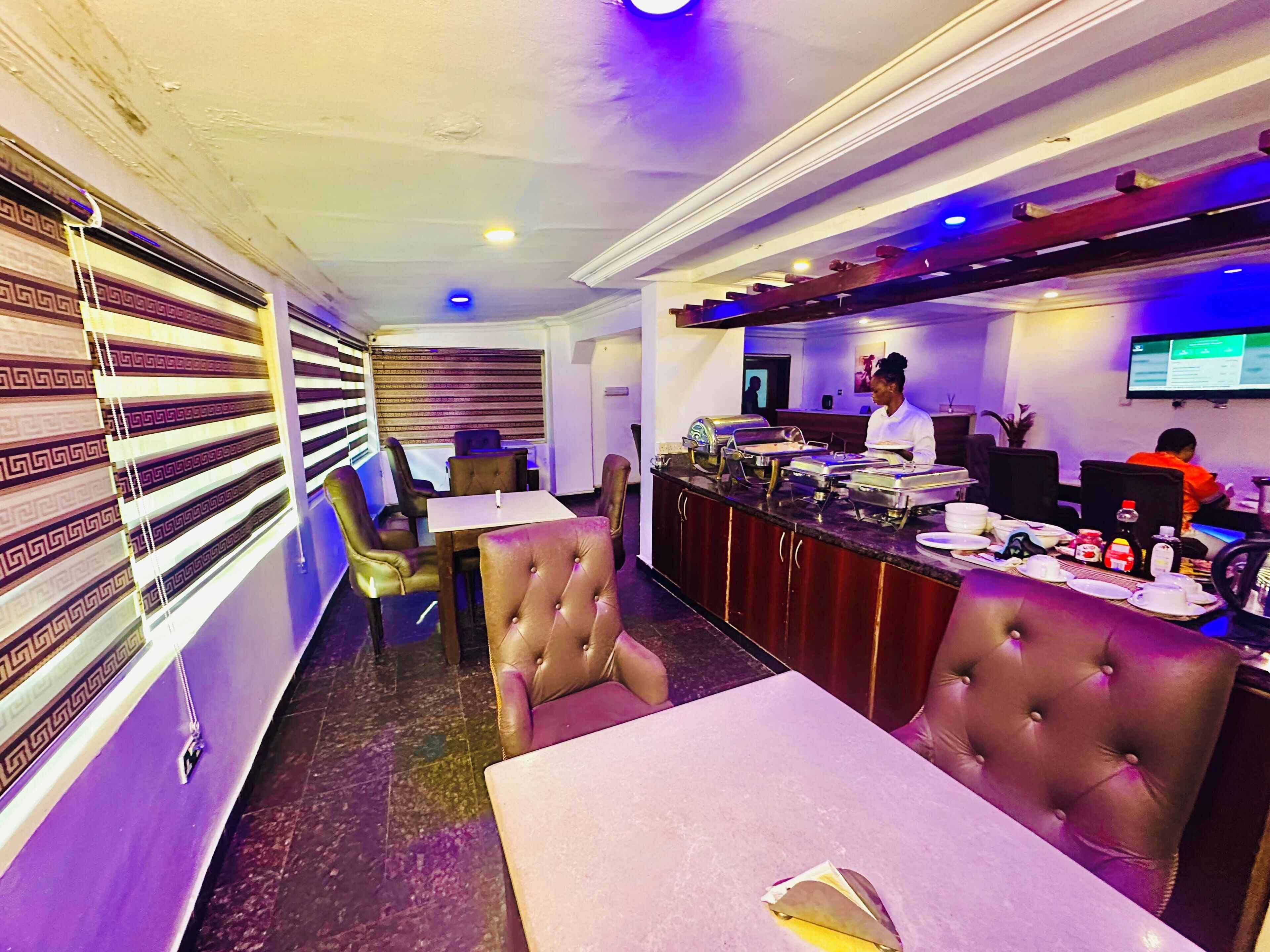 A restaurant with a buffet setup, leather seating, and a bar area.