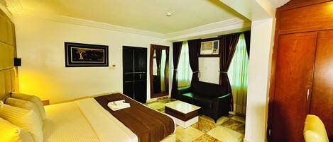 A hotel room with a bed, a sofa, a desk, and a wardrobe.
