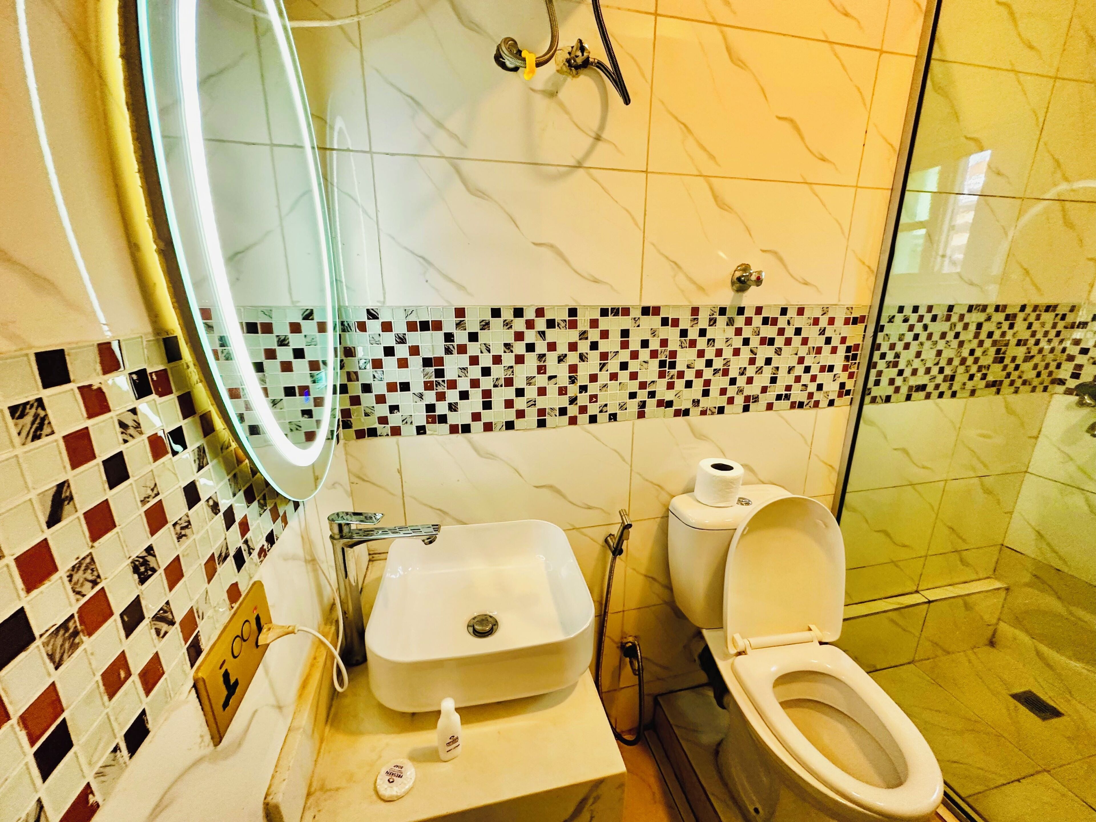 A bathroom with a sink, mirror, toilet, and shower.