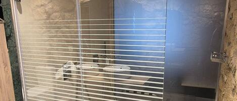 Un baño moderno con cabina de ducha de vidrio, suelo de mármol y pared de acento de piedra.