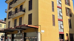 A yellow building with multiple balconies, a storefront with a sign, and a clear blue sky. - Silvia's house:cozy,comfortable.20 minutes walk from Lake Como (Como)