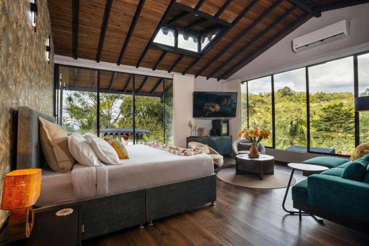 A modern bedroom with a large bed, a sofa, a coffee table, and a TV.