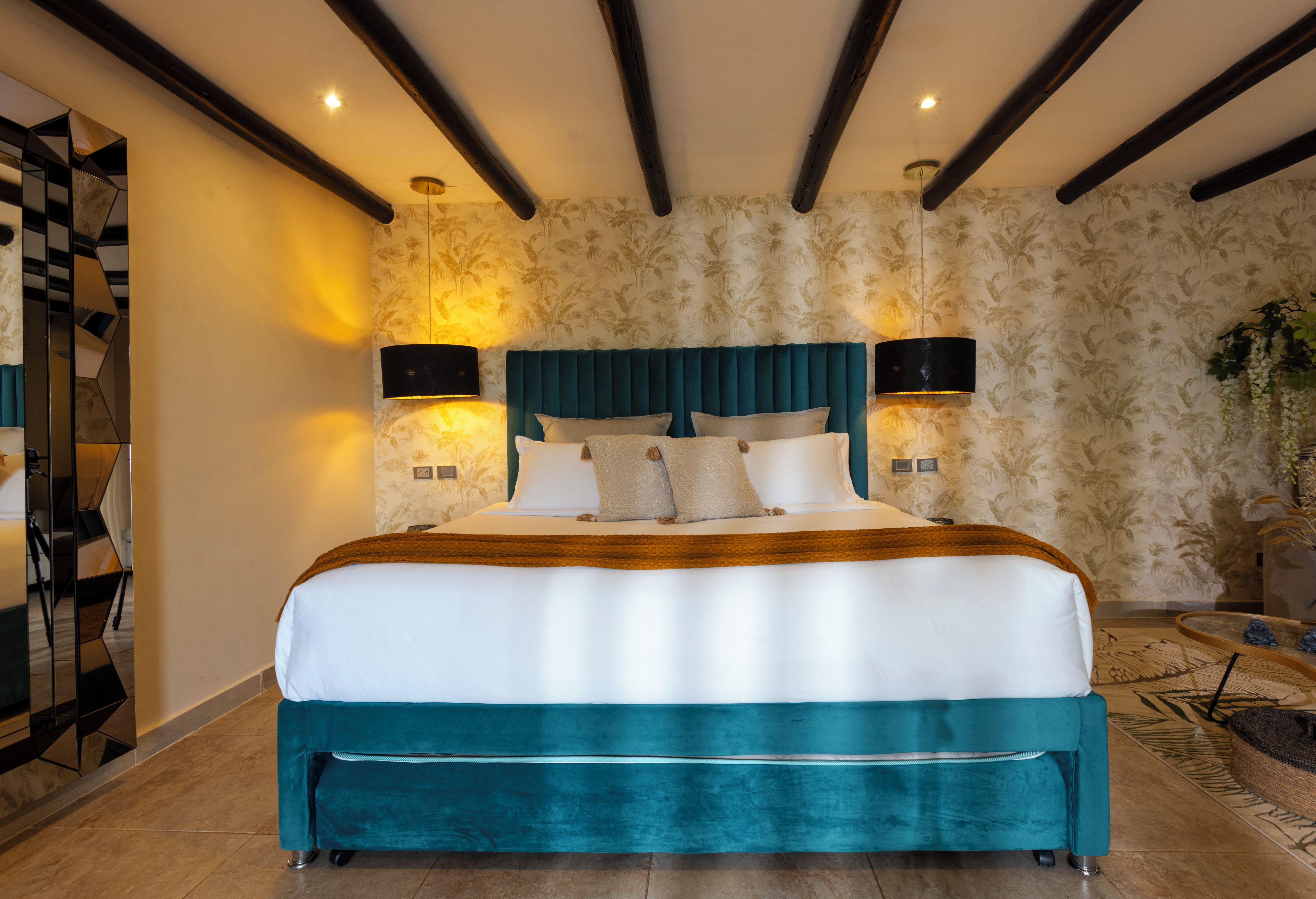 A bedroom with a large bed, two wall-mounted lamps, and a patterned wallpaper.