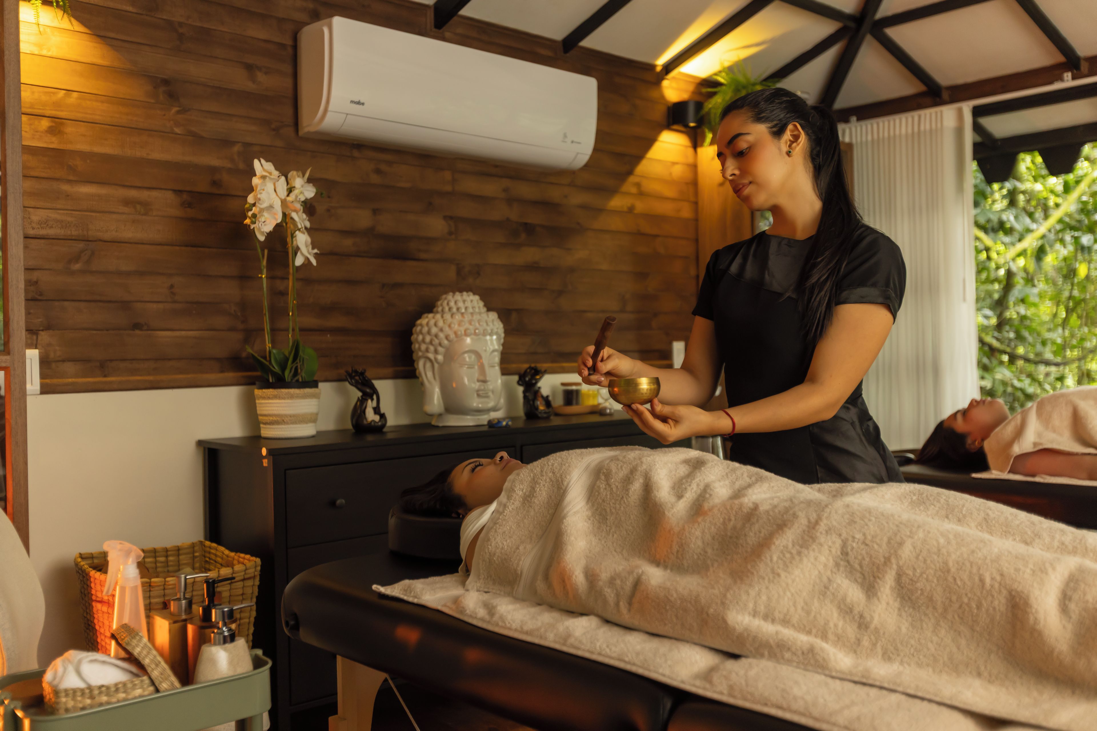 A massage therapy session in a room with wooden walls, a massage table, and a small Buddha statue.