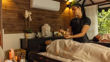 A massage therapy session in a room with wooden walls, a massage table, and a small Buddha statue.