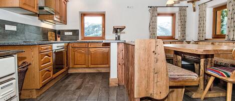 Una cucina rustica con mobili in legno, piano cottura integrato e un'isola grande con una panca.