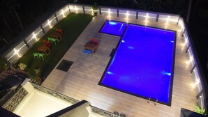 A rooftop pool area with a wooden deck, two swimming pools, and outdoor seating. - Encasa Resort  (Alibag)