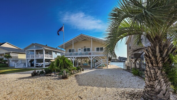 A beachfront hotel with a covered porch, a flag, and a palm tree.