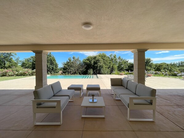 Relax by the pool in a serene outdoor seating area with a sofa, armchairs, and ottomans.