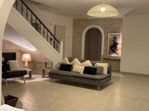Relax in this stylish living room with a comfortable sofa, staircase, and large window.