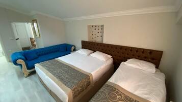 Une chambre d’hôtel avec deux lits, un canapé bleu et un panneau décoratif au mur.
