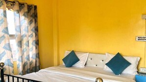 A room with a bed, a window with curtains, an air conditioning unit, and a wall socket. - The Hostel Crown (Udaipur)