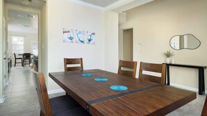 A dining area with a wooden table, four chairs, and three blue decorative items on the table. - Arcade, Billiards with a non heated Pool Two master suites (San Antonio)