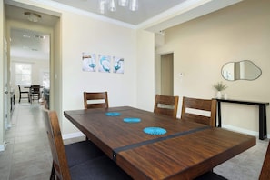 A dining area with a wooden table, four chairs, and three blue decorative items on the table. - Arcade, Billiards with a non heated Pool Two master suites (San Antonio)