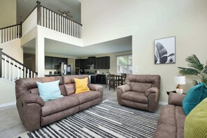 A spacious living room with a brown leather sofa, a striped rug, and a dining area in the background. - Arcade, Billiards with a non heated Pool Two master suites (San Antonio)