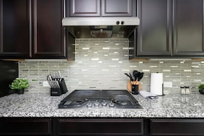 A modern kitchen with dark cabinets, a stainless steel range, a tiled backsplash, granite countertops, and a gas stove. - Arcade, Billiards with a non heated Pool Two master suites (San Antonio)