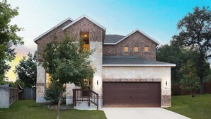 A two-story house with a stone facade, a garage, and a small front yard with a tree. - Arcade, Billiards with a non heated Pool Two master suites (San Antonio)