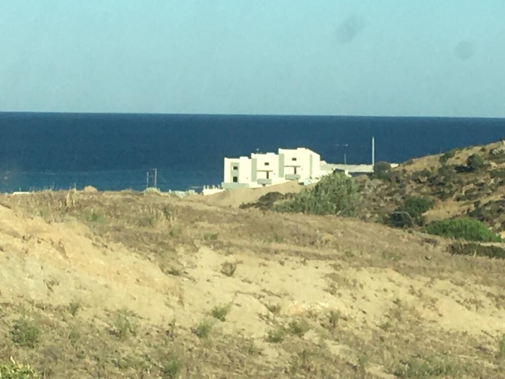 Paisatge costaner amb un edifici en un turó, amb vista al mar.