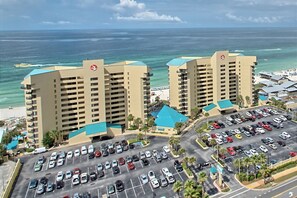 A high-rise hotel with a parking lot and ocean view.