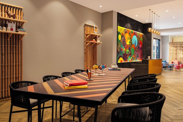 Une salle de conférence avec une longue table, des chaises noires et un tableau abstrait aux couleurs vives accroché au mur.