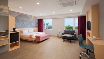 A hotel room with a bed, desk, chair, and large windows.