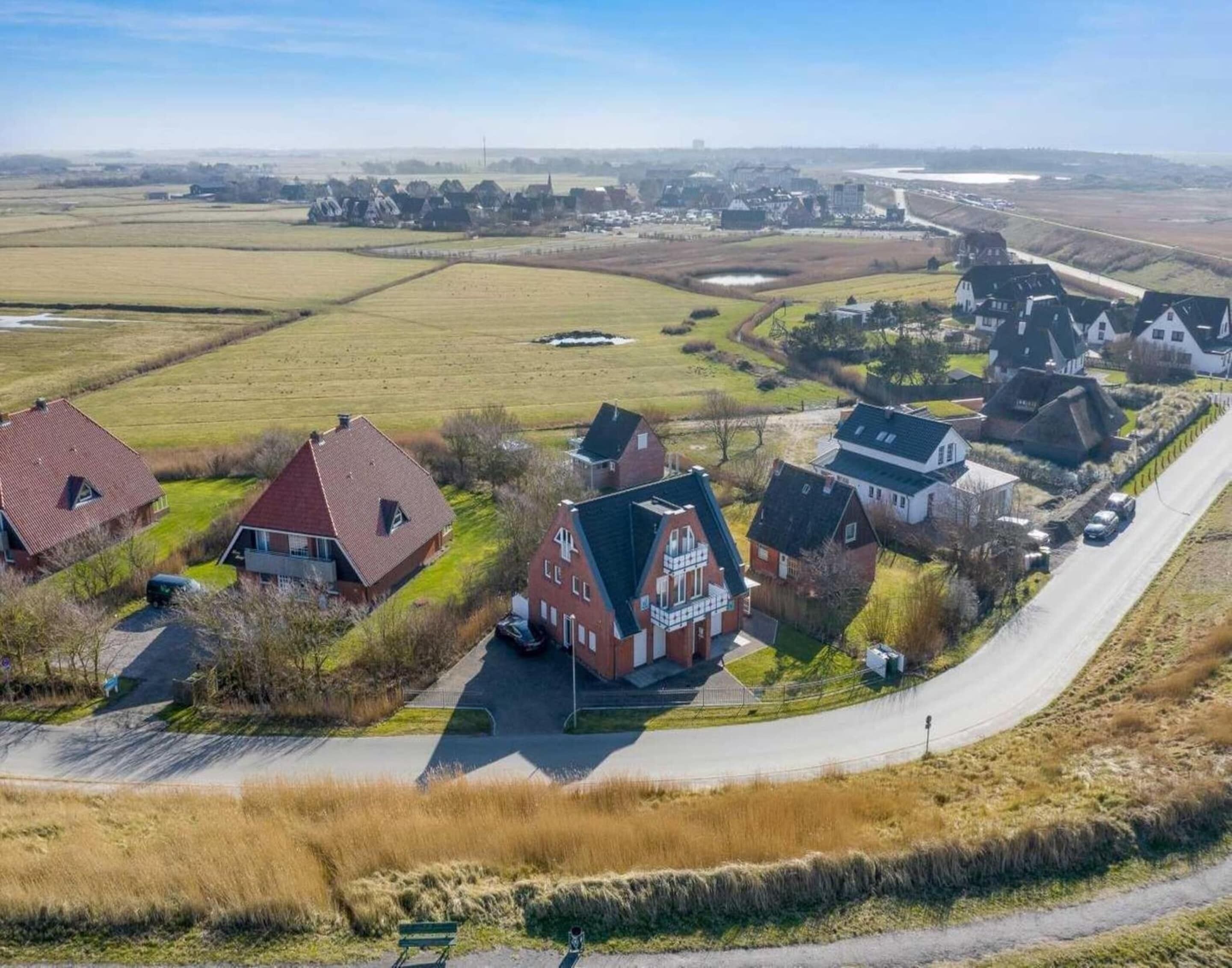 An aerial view of a rural area with houses, a road, and fields.