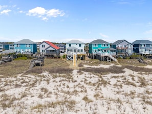 Ein Strandgrundstück mit mehreren Häusern, jedes mit einer Terrasse und einer Treppe zum Strand.