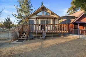 Une maison à deux étages avec une terrasse, deux chaises et un espace extérieur abrité.