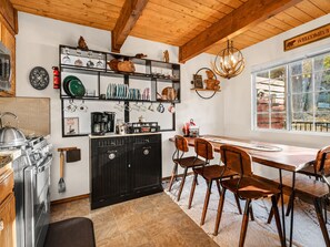 Una cocina con armarios de madera, una estufa y un comedor con sillas y una mesa.