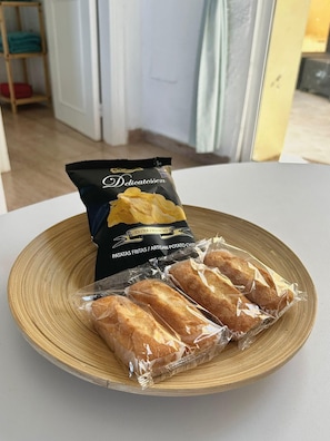 Un piatto con un sacchetto di patatine e tre baguette su un tavolo di legno.