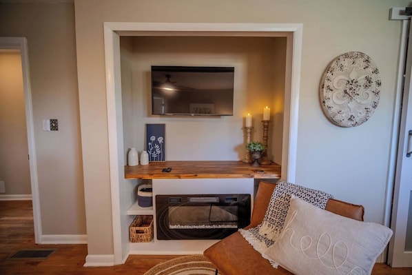 Uma sala de estar acolhedora com lareira, televisão na parede e um objeto decorativo.
