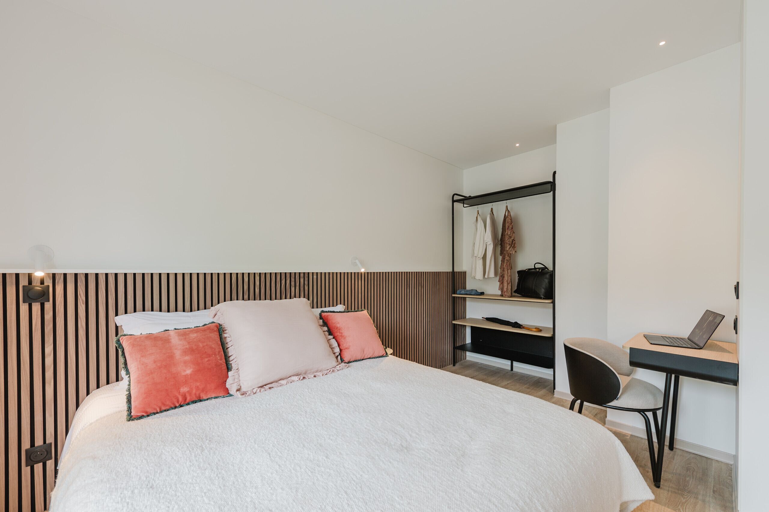 Une chambre moderne avec un grand lit, un bureau avec un ordinateur portable et une armoire.