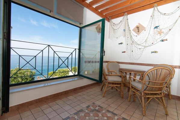 A balcony with a view of the sea, wicker furniture, and decorative nets. - Sunny Beach Apartment (Piran)