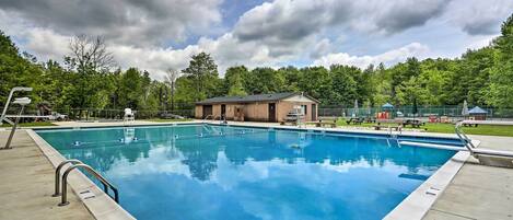 A rectangular swimming pool with a metal handrail on one side, surrounded by a concrete deck.