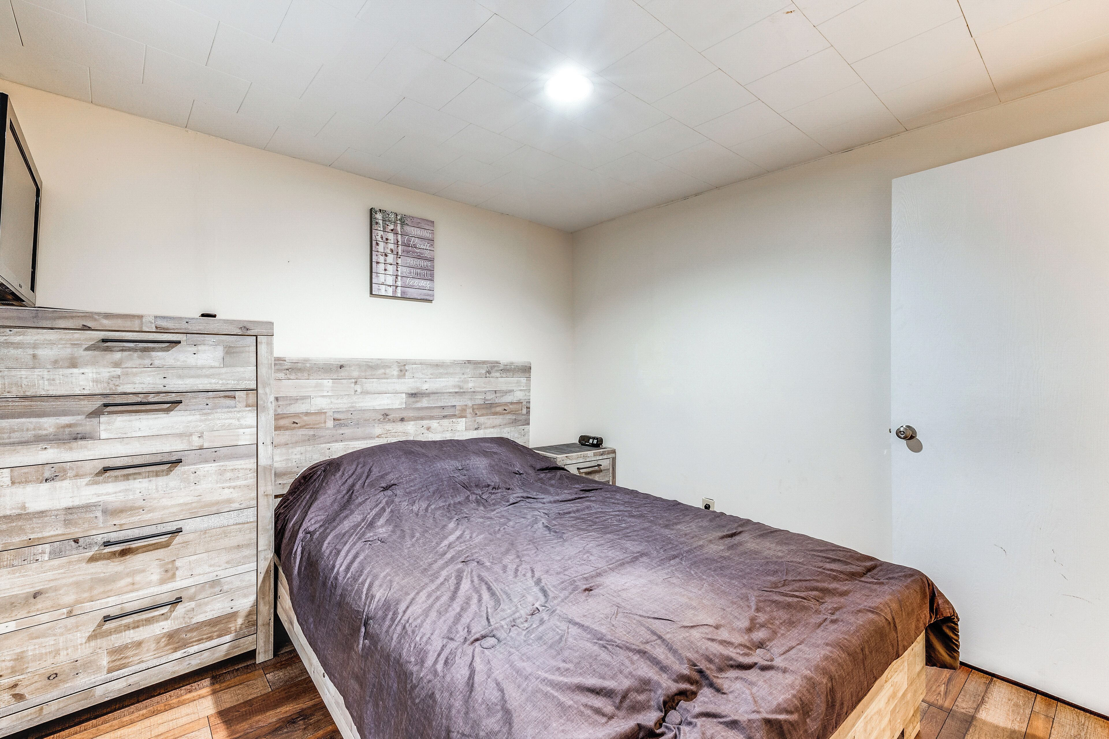 Ein Schlafzimmer mit einem Bett, einer Holzkommode und einer weißen Tür.