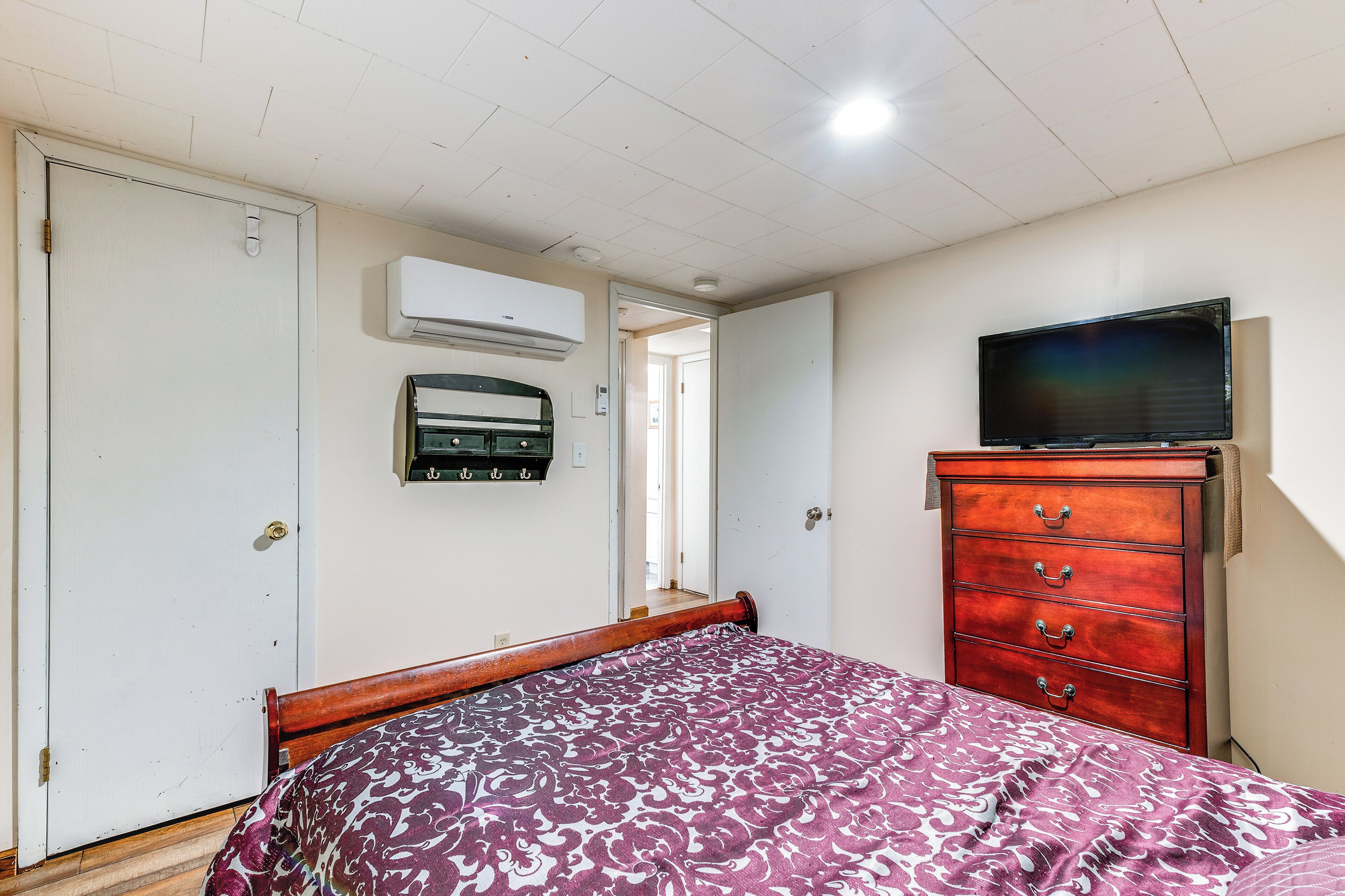 Ein Schlafzimmer mit Bett, Kommode, Fernseher und Klimaanlage.