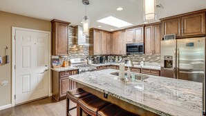 A modern kitchen with granite countertops, stainless steel appliances, and wooden cabinets.