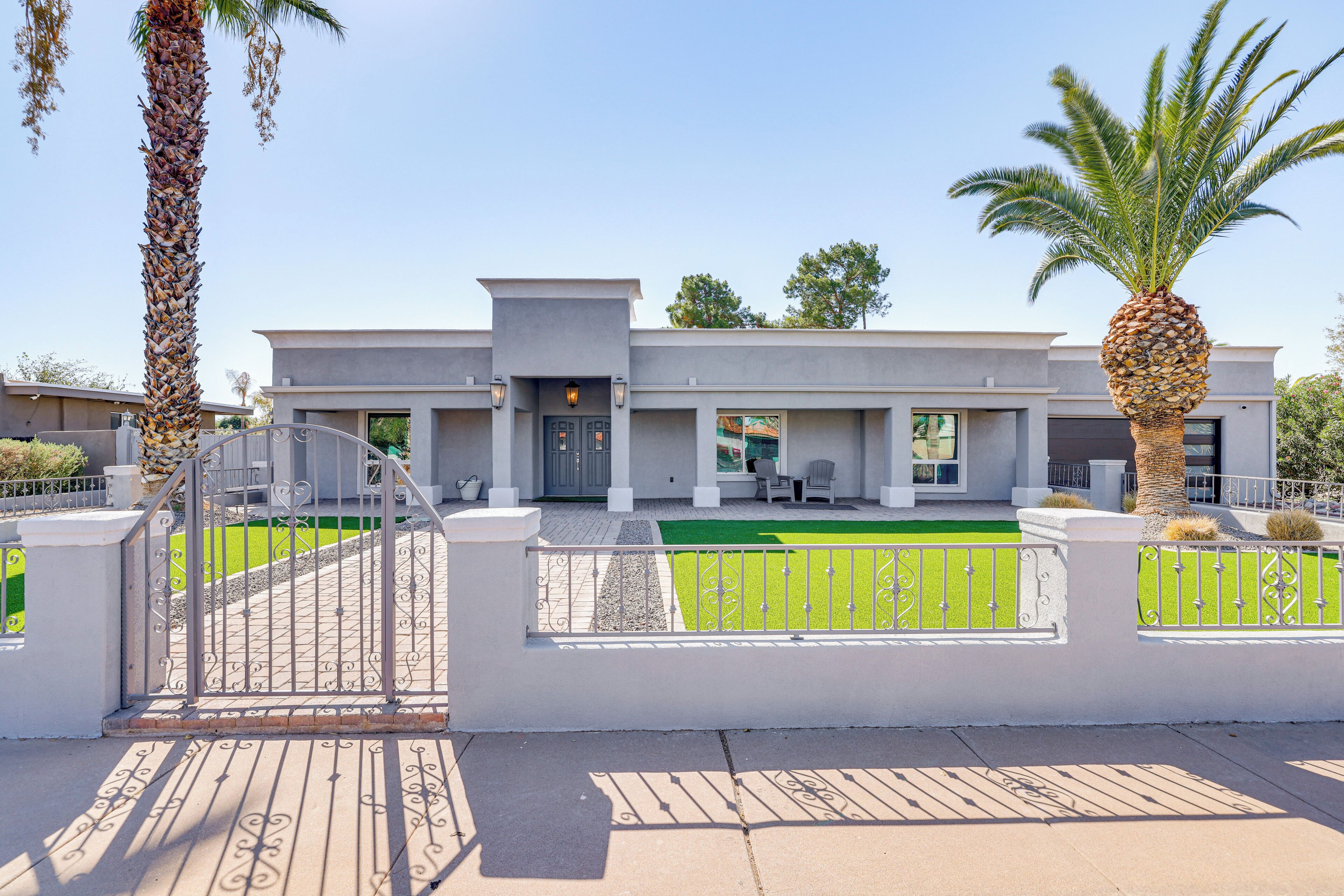 A modern two-story house with a covered patio, a gated entrance, and a well-maintained lawn.