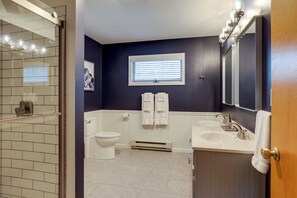 Un baño con inodoro, lavamanos y zona de ducha.