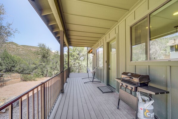 A covered porch with a grill and propane tank, overlooking a natural landscape. - Games & Outdoor Seating: Cabin in Scenic Payson! (Payson)