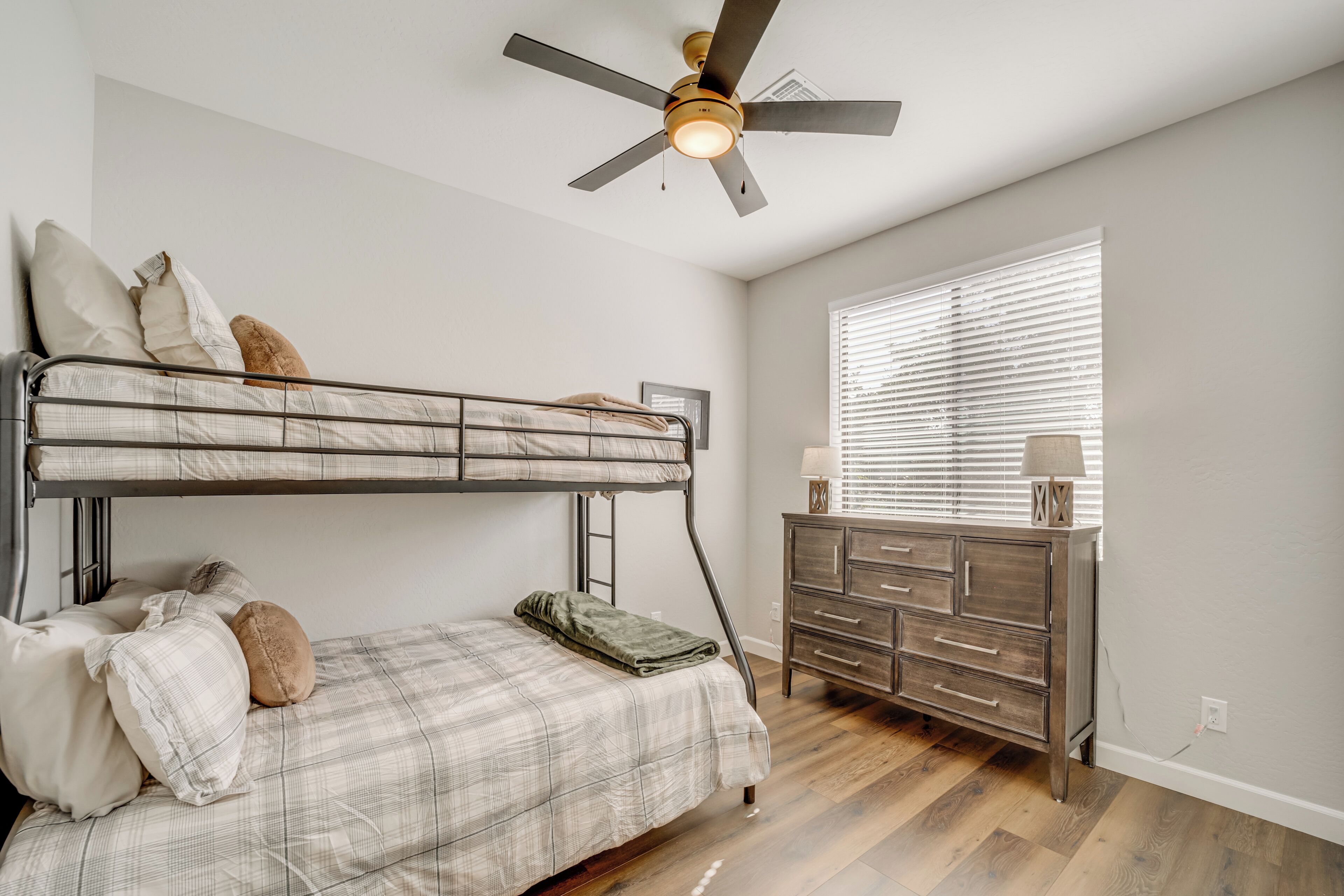 A bedroom with a bunk bed, a dresser, and a ceiling fan.