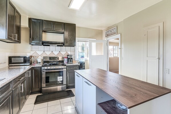 A modern kitchen with dark cabinets, stainless steel appliances, and a wooden countertop. - Oakland Apartment: 8 Mi to Dtwn! (Oakland)