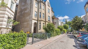 A street view with a building featuring a large arched entrance, multiple windows, and a balcony. - Imperial Apartments - Sopocki Style  (Sopot)
