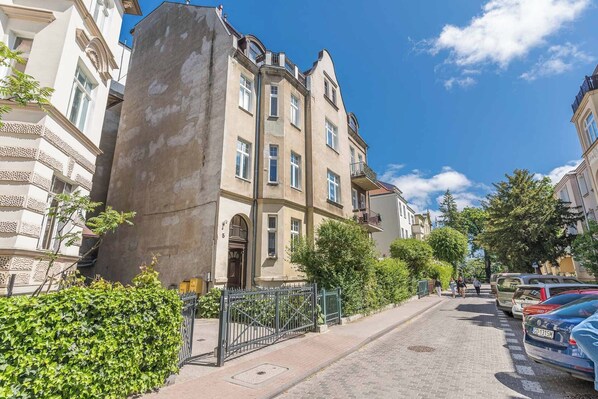 A street view with a building featuring a large arched entrance, multiple windows, and a balcony. - Imperial Apartments - Sopocki Style  (Sopot)