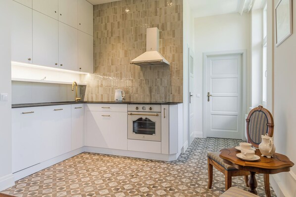 Una cocina moderna con armarios blancos, horno empotrado y salpicadero de azulejos.