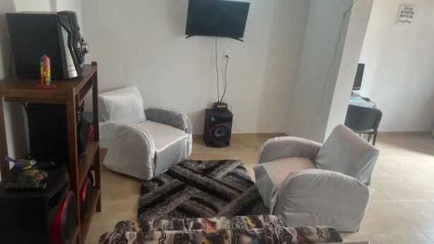 A living room with two white sofas, a patterned rug, a TV mounted on the wall, and a speaker. - Country apartment (Ibague)