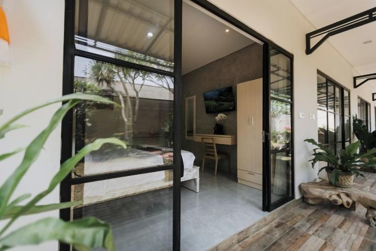 A modern interior with a glass door leading to a balcony, a wooden dining table, and a TV mounted on the wall.