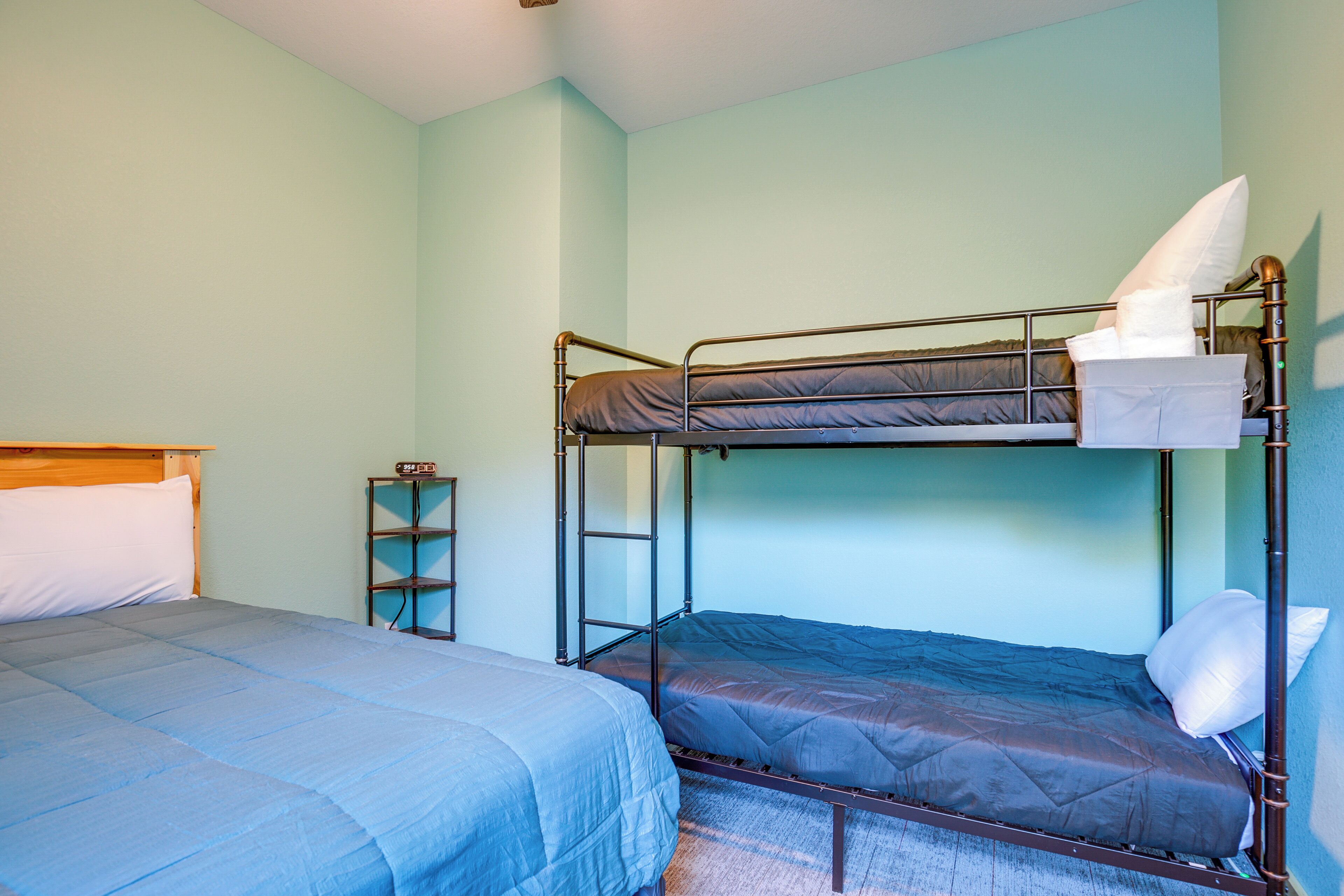 A room with a bunk bed, a single bed, and a small shelf unit.
